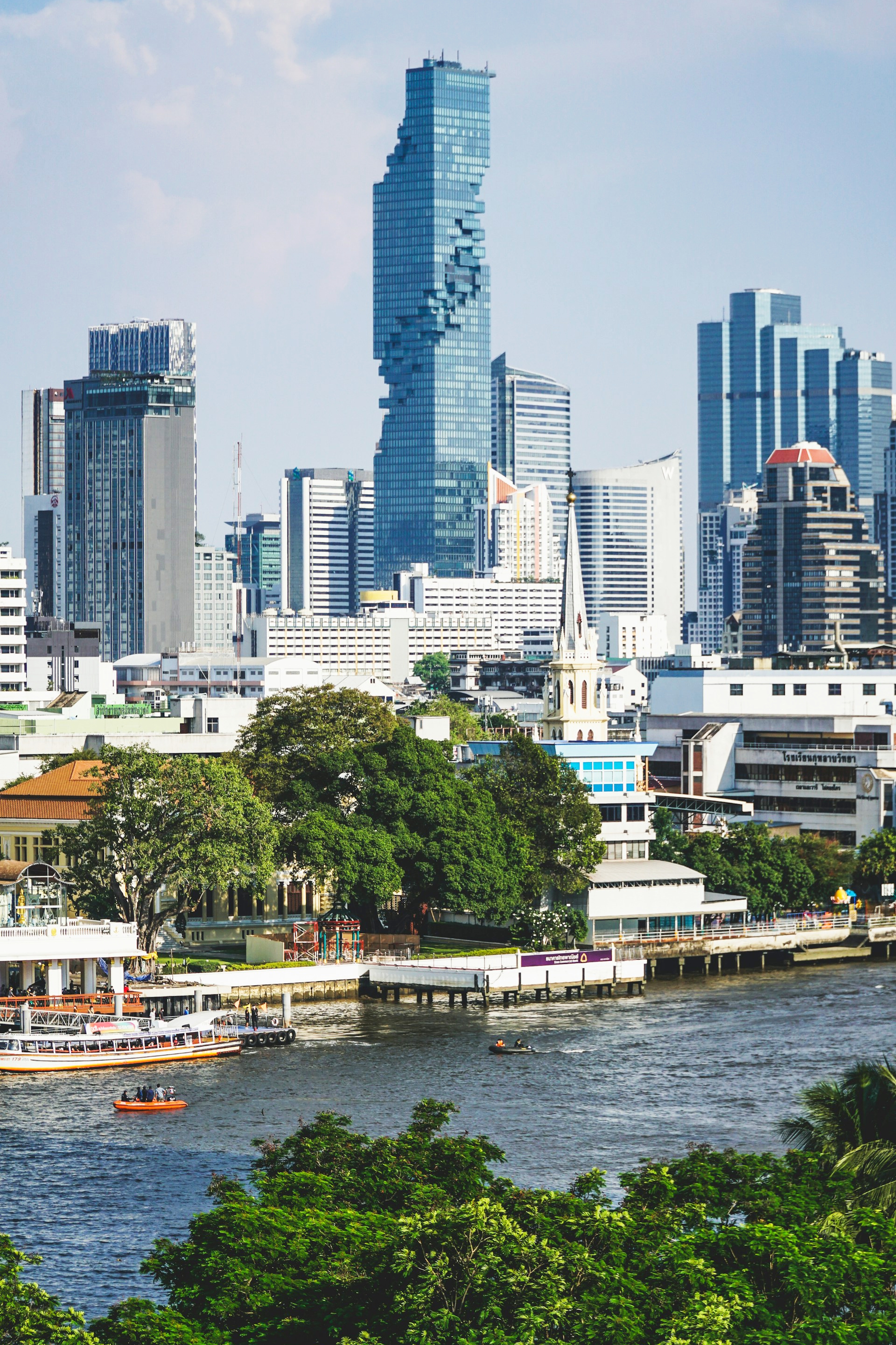 Bangkok skyline along the Chao Phraya River with modern skyscrapers and riverboats