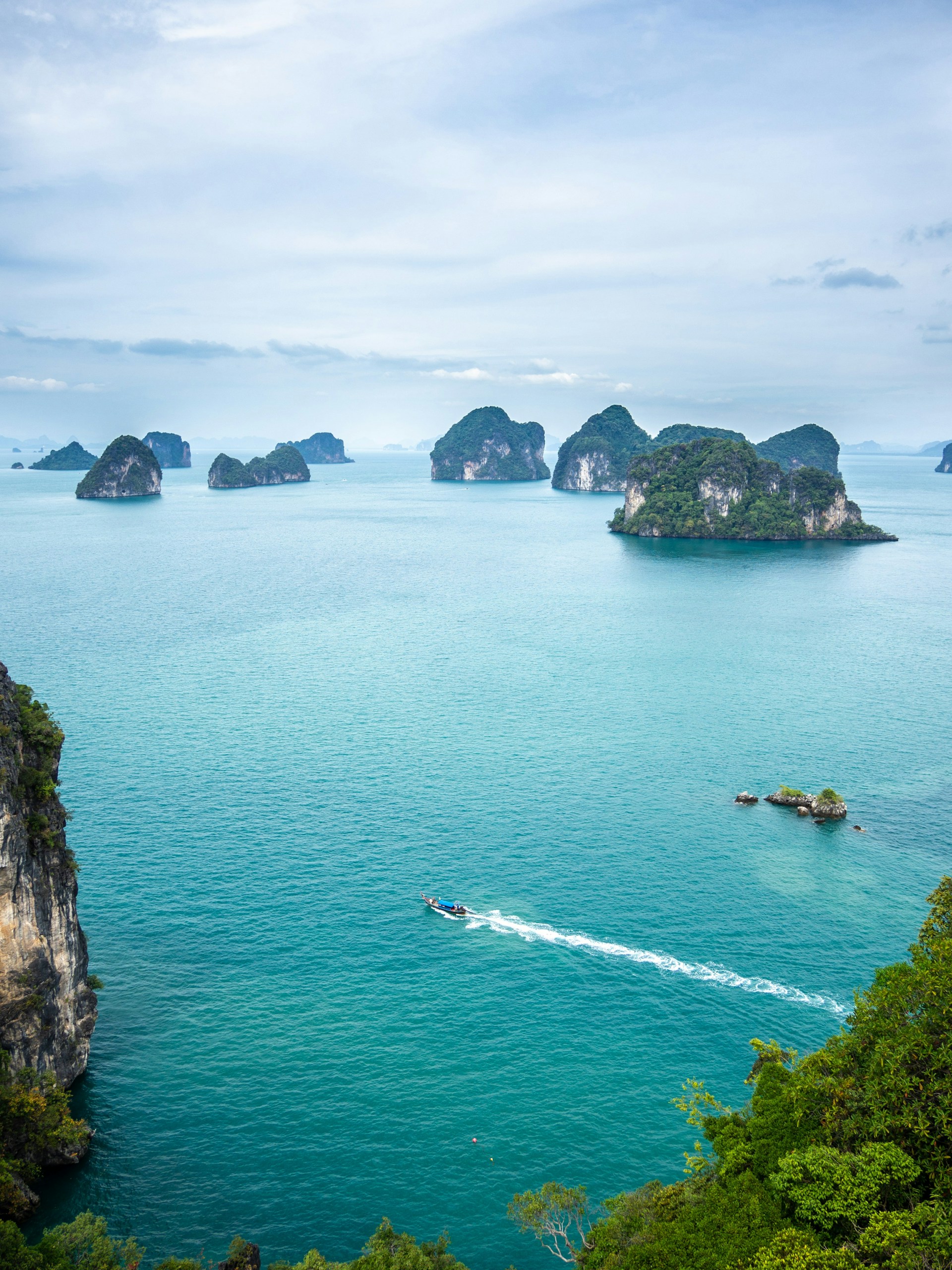 Limestone islands in southern Thailand with turquoise water and a long-tail boat